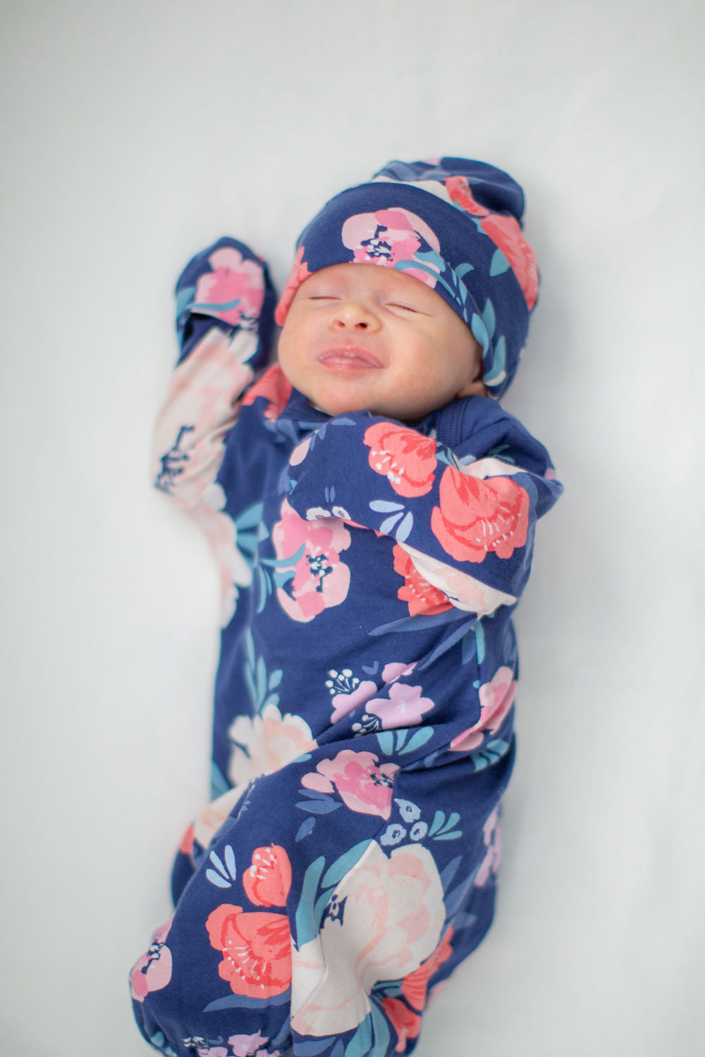 Annabelle printed baby gown and hat. Cream and pink flowers against a navy background.