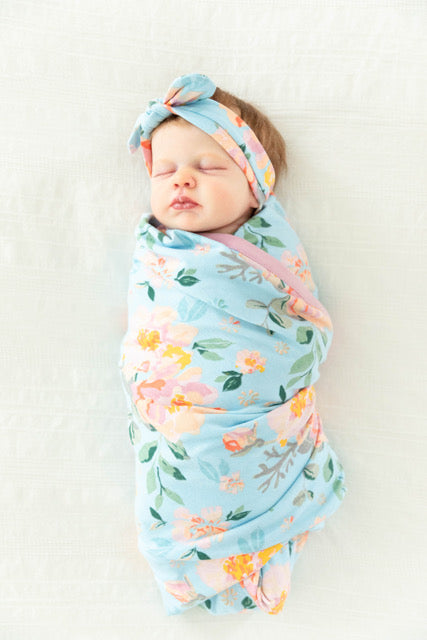 Beautiful pink, peach, and orange floral pattern against a light blue background. Swaddle your baby in the perfect Jade printed blanket. 