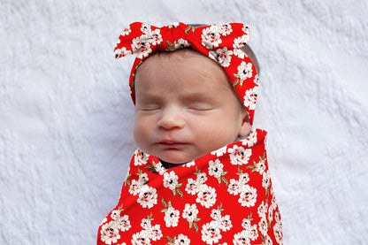 Sadie print swaddle with white flowers against a red background.