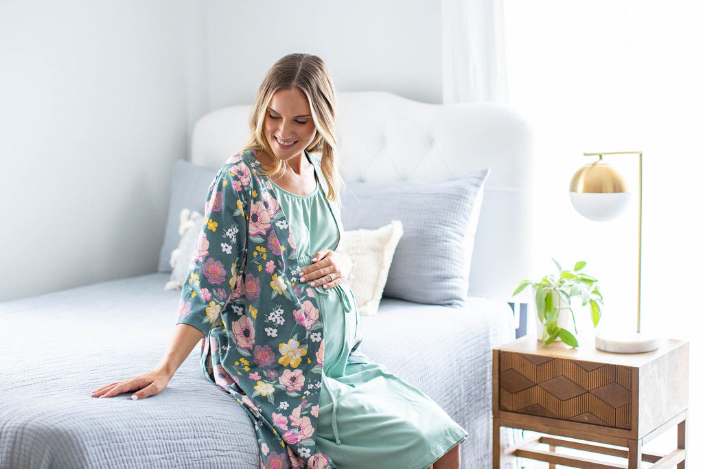 Charlotte maternity robe with pockets, belt closure, and knee length. Pink and yellow flowers against green background.